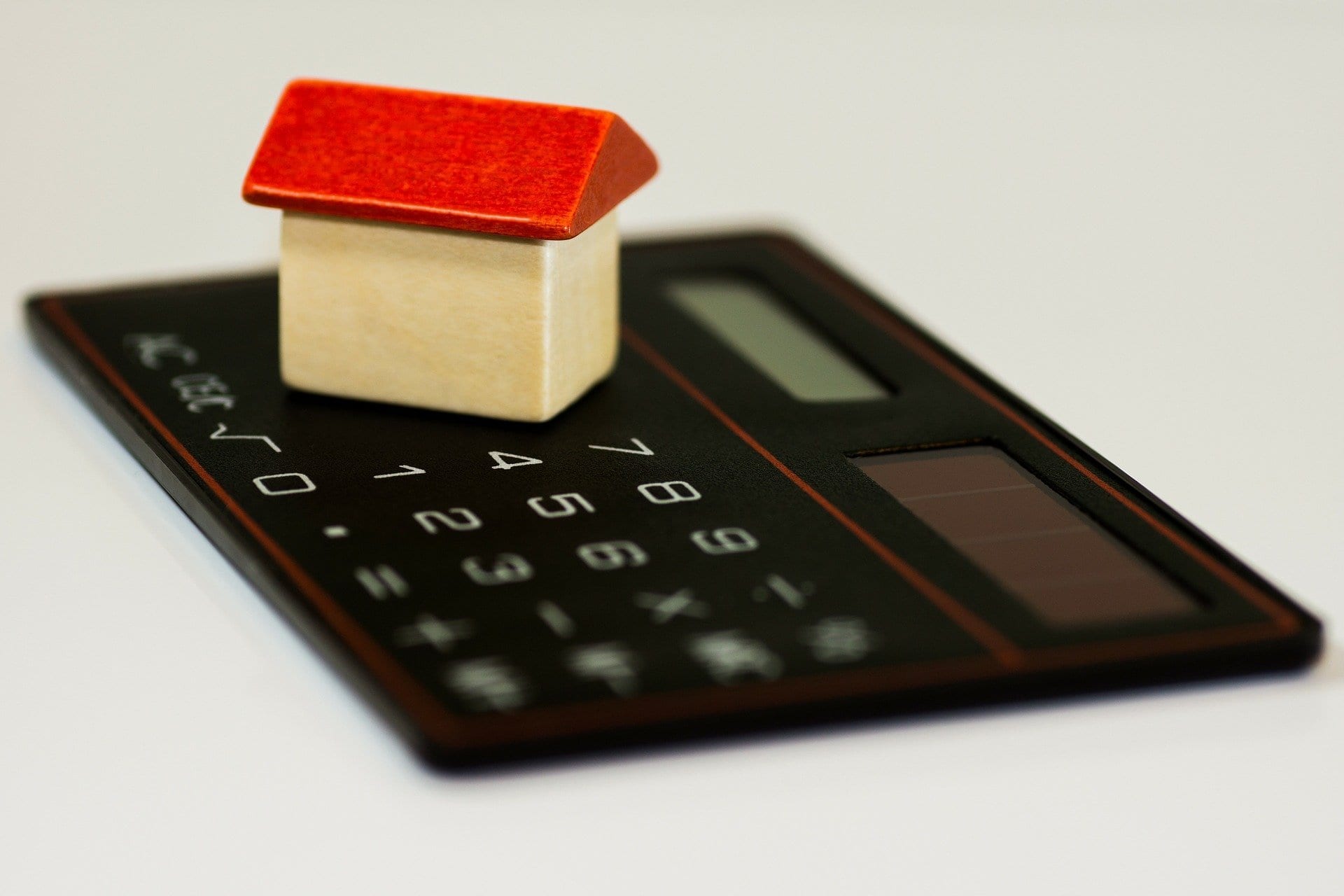 Calculator and small house representing debt restructuring